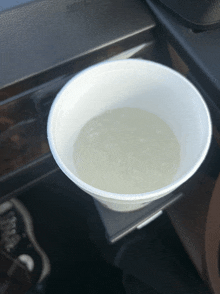 a plastic cup filled with liquid sits on a car dashboard