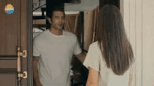 a man and a woman are standing in front of a door and looking at each other .