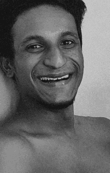 a black and white photo of a smiling shirtless man