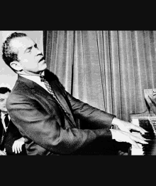 a man in a suit and tie is playing a piano in a black and white photo