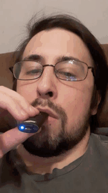 a man with glasses and a beard is holding a small object in his hand