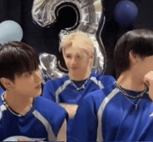 a group of young men in blue shirts are sitting next to each other in front of a balloon .