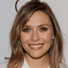 a close up of a woman 's face with long hair and a white shirt .