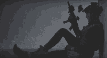 a silhouette of a soldier sitting on the floor holding a rifle