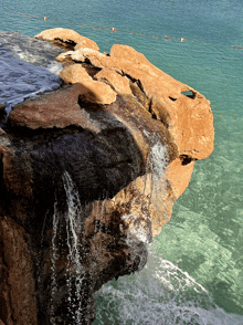 a waterfall is surrounded by rocks in the ocean