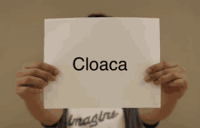 a person holding up a piece of paper with cloaca written on it