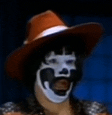 a man wearing a cowboy hat and a clown mask