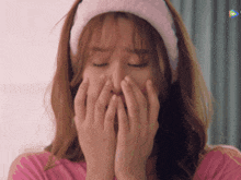 a woman wearing a headband and covering her face with her hands