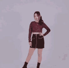 a woman is dancing in a crop top and black skirt .