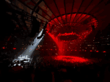 a crowd of people are watching a concert in a stadium with red lights