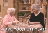 two elderly women are sitting at a table talking to each other .