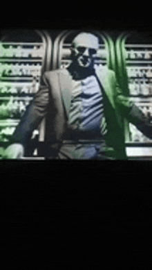 a man in a suit and sunglasses is standing in front of a shelf .