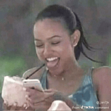 a woman is laughing while looking at her phone with a straw in her mouth