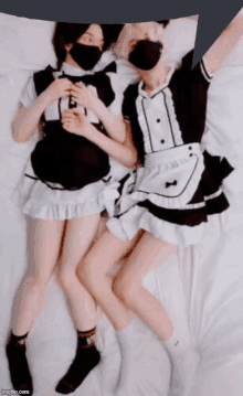 two maids are laying on a bed with a speech bubble in the background