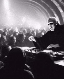 a man in a black robe is playing a dj set in front of a crowd of people