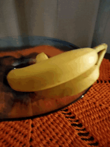 a banana is sitting in a glass bowl on a table