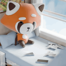 a stuffed animal is sitting on a bed next to a phone and origami