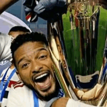 a man is holding a trophy in his hands and smiling with his mouth open .