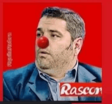 a man with a red clown nose is wearing a rascon logo .