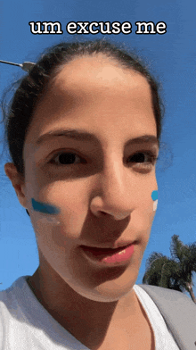 a woman with blue and white paint on her face has the words um excuse me above her face