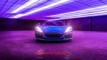 a blue sports car is parked in a garage with purple lights behind it