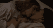 a man and a woman are kissing while laying on a bed