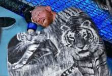 a man is sleeping in a cage with a tiger on his back .