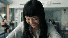 a woman with long black hair is smiling in a room