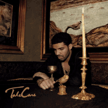 a man sitting at a table with a candle and a candle holder that says take care on the bottom