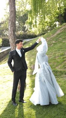 a man in a suit and tie stands next to a woman in a blue dress