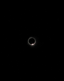 a ring of light around a black circle in the night sky