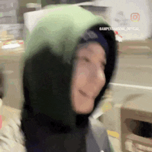 a person wearing a green hoodie is smiling and looking at the camera .