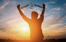 a silhouette of a man breaking chains with his arms in the air