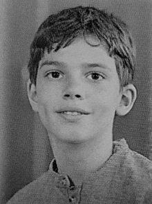 a black and white photo of a young boy with a smile on his face