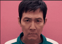 a close up of a man 's face in front of a pink wall