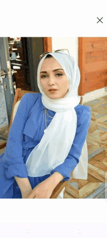 a woman wearing a blue dress and a white scarf