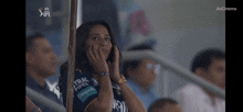 a woman sitting in a stadium watching a ipl match