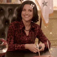 a woman wearing a leopard print shirt is smiling