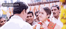 a bride and groom are standing next to each other in front of a crowd of people at a wedding .