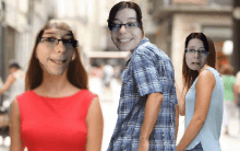 a woman in a red dress and a man in a plaid shirt are walking down the street