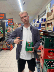 a man holds a can of heineken beer in a store