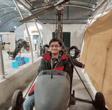 a boy in a red jacket is sitting in a small vehicle