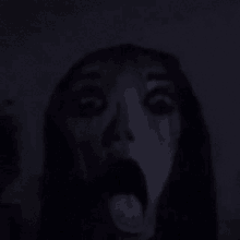 a close up of a person 's face with their mouth open in the dark