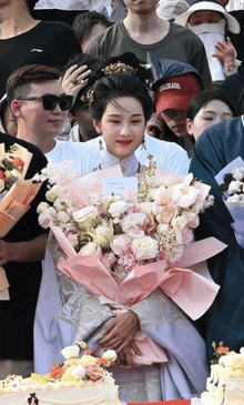 a woman in a white dress is holding a bouquet of pink flowers