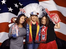 three women are posing in front of an american flag and one has a foam finger that says us on it