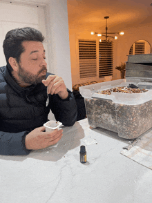 a man sitting at a table with a bottle of essential oil