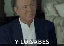 a man in a suit and white shirt is making a funny face and saying y lo sabes .