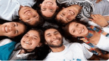 a group of young people are laying in a circle and smiling for the camera .