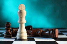 a white chess piece is standing in the middle of a chess board surrounded by brown chess pieces .