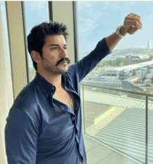 a man with a mustache is standing in front of a balcony